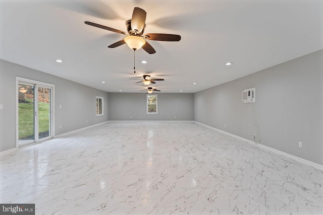 unfurnished room featuring a wall unit AC, a wealth of natural light, and ceiling fan