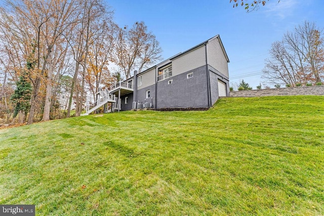 back of house with a garage, a deck, and a lawn