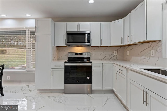 kitchen featuring light stone countertops, stainless steel appliances, white cabinetry, and tasteful backsplash