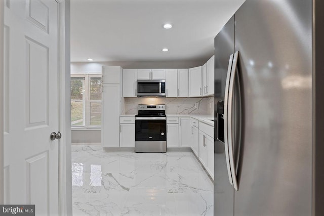 kitchen featuring decorative backsplash, white cabinetry, and appliances with stainless steel finishes