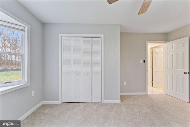 unfurnished bedroom with multiple windows, ceiling fan, a closet, and light colored carpet