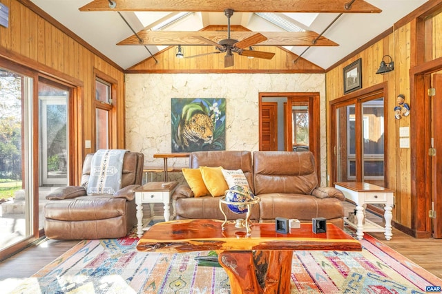 living room with beam ceiling, wood walls, ceiling fan, and light wood-type flooring