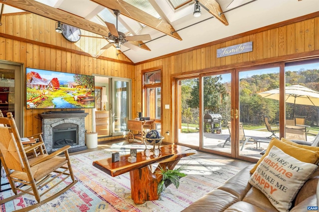 interior space featuring wooden walls, a skylight, ceiling fan, light wood-type flooring, and beam ceiling