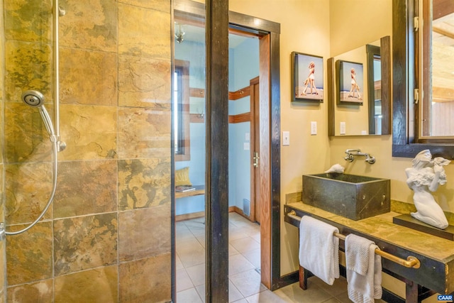 bathroom with a tile shower, tile patterned flooring, and vanity