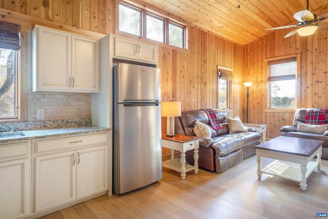 kitchen with wood walls, stainless steel fridge, lofted ceiling, and wooden ceiling