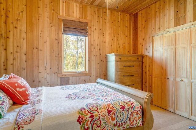 bedroom with a closet, wood walls, light hardwood / wood-style flooring, and wood ceiling