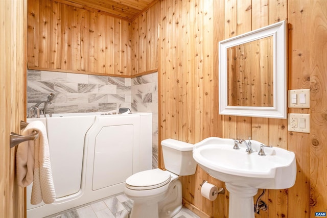 bathroom with wood walls and toilet