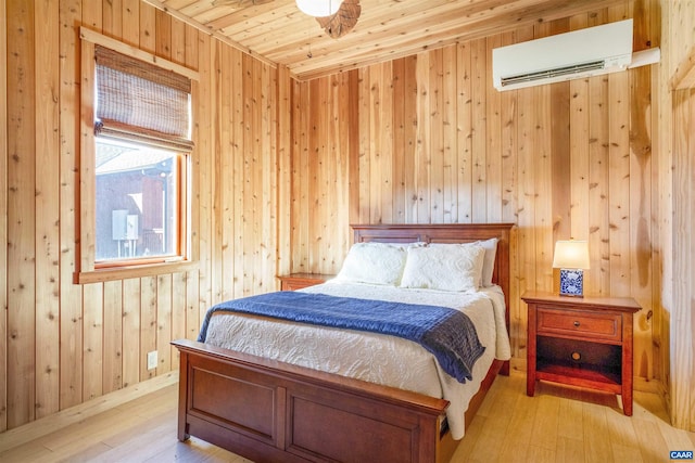 bedroom with light wood-type flooring, a wall unit AC, wood ceiling, and wood walls