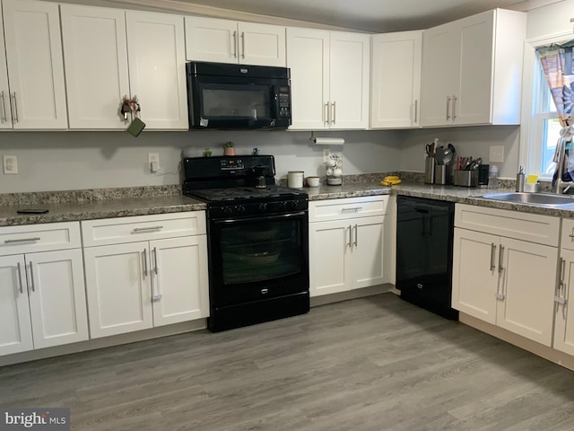 kitchen featuring white cabinetry, sink, black appliances, and light wood-type flooring