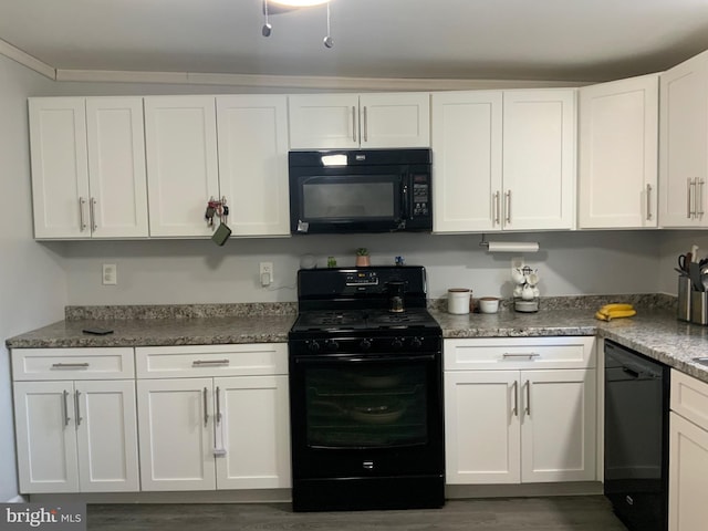 kitchen with dark stone countertops, dark wood-type flooring, white cabinets, and black appliances