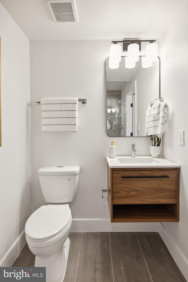 bathroom featuring wood-type flooring, vanity, and toilet