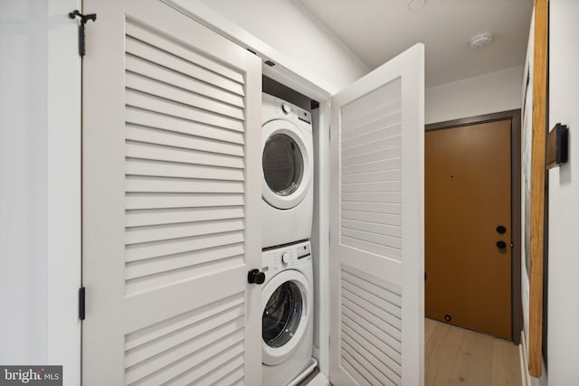 clothes washing area featuring stacked washer / drying machine and light wood-type flooring