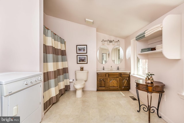 bathroom featuring toilet, vanity, vaulted ceiling, and washer / dryer