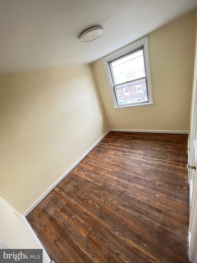 unfurnished room with dark hardwood / wood-style floors and vaulted ceiling