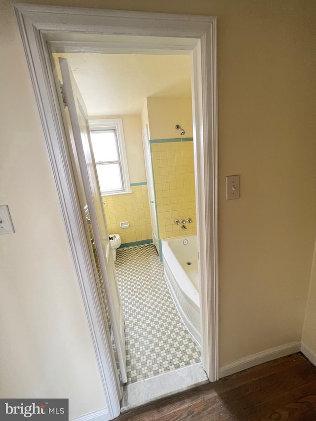 bathroom with wood-type flooring, tiled shower / bath combo, and toilet