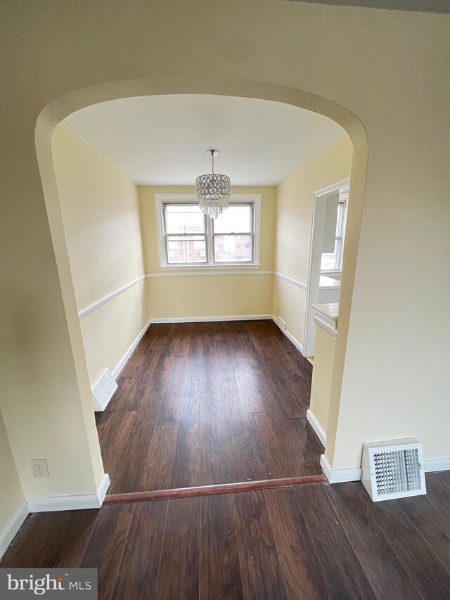 unfurnished dining area with dark wood-type flooring and a chandelier