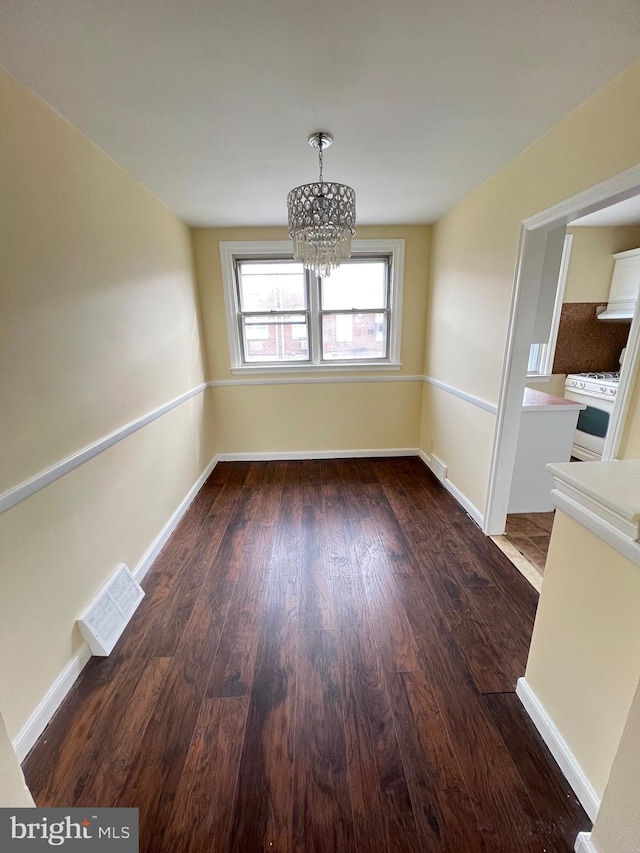 unfurnished dining area with a chandelier and dark hardwood / wood-style floors