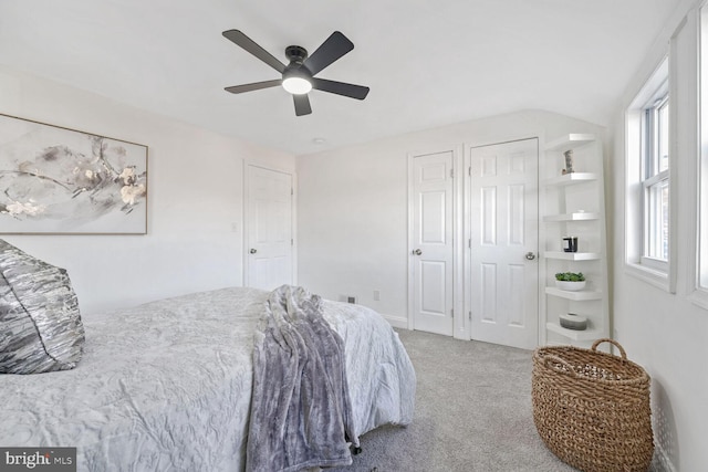 carpeted bedroom with ceiling fan and two closets