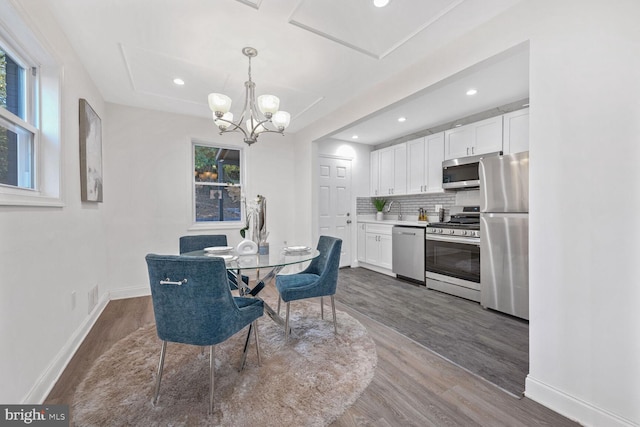 dining space with hardwood / wood-style flooring and an inviting chandelier