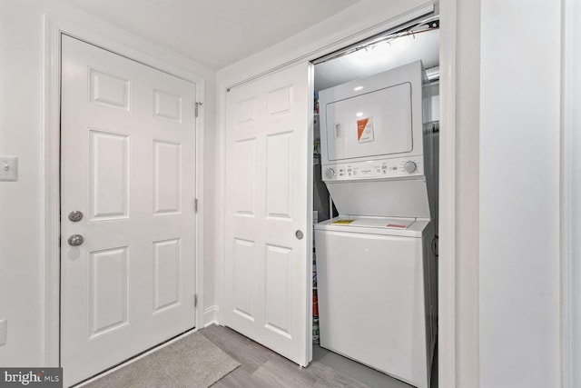 washroom with stacked washer / dryer and light hardwood / wood-style flooring