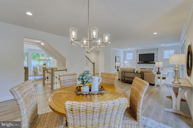 dining space with light wood-type flooring, ornamental molding, and an inviting chandelier