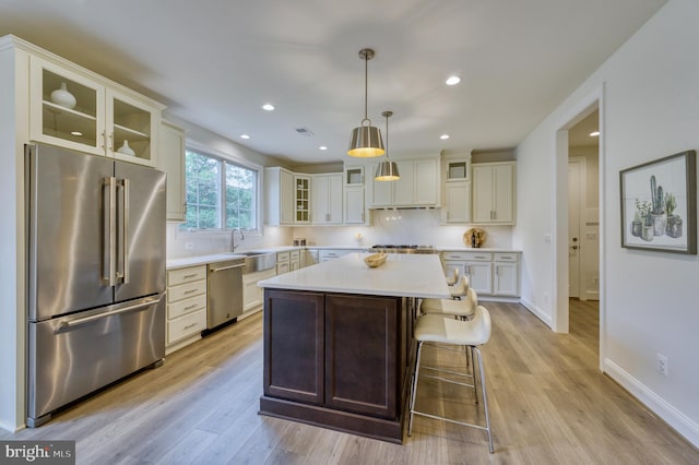 kitchen with a center island, stainless steel appliances, hanging light fixtures, and light hardwood / wood-style flooring