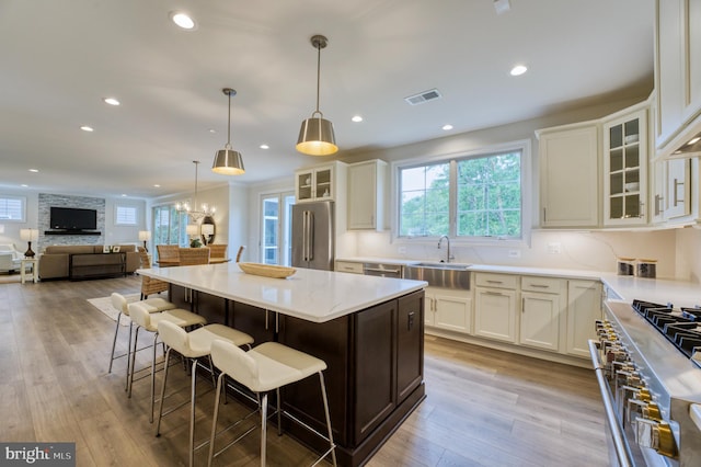 kitchen with light wood-type flooring, high end appliances, sink, a kitchen island, and a breakfast bar area