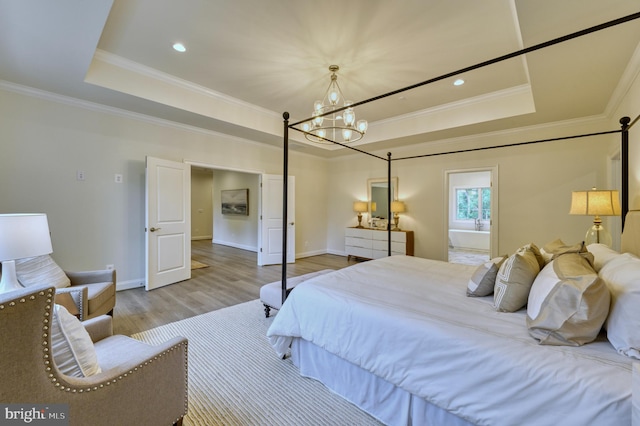 bedroom with a notable chandelier, light wood-type flooring, ornamental molding, and a tray ceiling