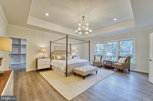 bedroom featuring a tray ceiling, crown molding, and light wood-type flooring