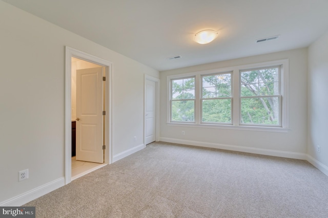 unfurnished bedroom featuring light colored carpet and multiple windows