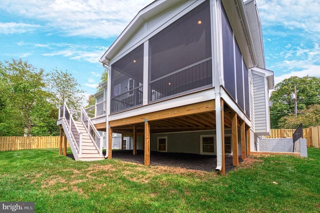 back of house with a lawn, a sunroom, and a wooden deck