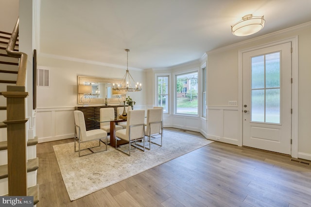 dining room featuring light hardwood / wood-style floors, an inviting chandelier, and crown molding