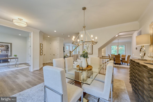 dining space featuring light hardwood / wood-style floors, ornamental molding, and an inviting chandelier