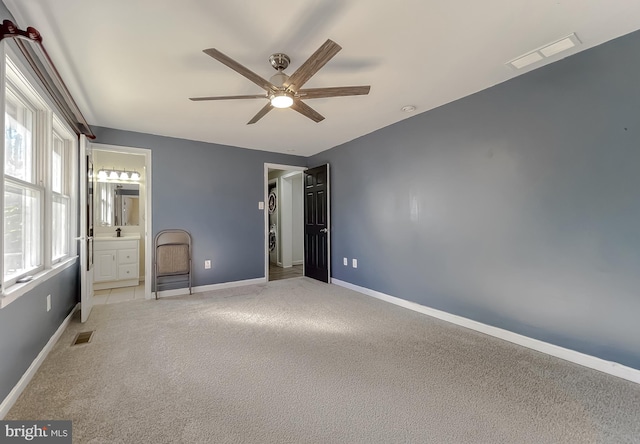 unfurnished bedroom featuring ensuite bathroom, ceiling fan, and light colored carpet