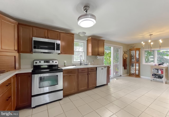 kitchen featuring appliances with stainless steel finishes, light tile patterned floors, a notable chandelier, and sink