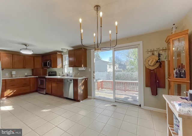 kitchen featuring stainless steel appliances, sink, light tile patterned floors, decorative light fixtures, and a notable chandelier