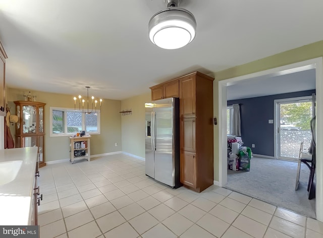 kitchen with pendant lighting, light carpet, sink, stainless steel fridge, and a notable chandelier