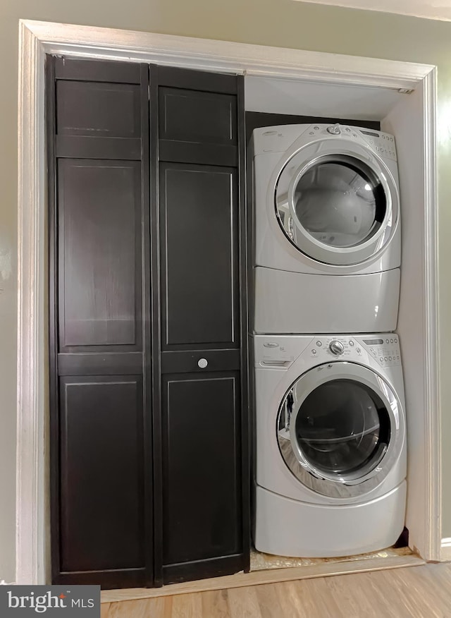 laundry area with light hardwood / wood-style flooring and stacked washer / dryer