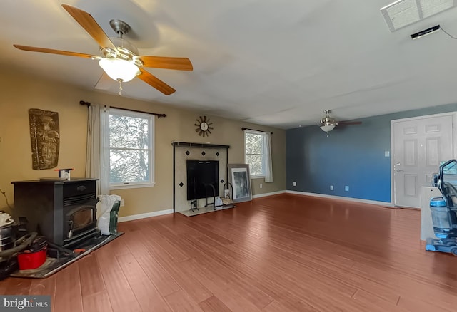 living room with a wood stove, ceiling fan, and hardwood / wood-style flooring