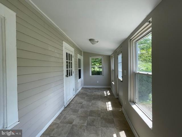 unfurnished sunroom featuring vaulted ceiling and a healthy amount of sunlight