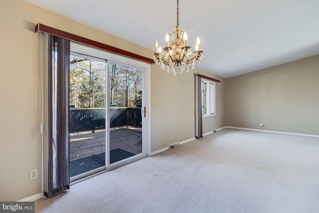 spare room with carpet flooring, a chandelier, and a healthy amount of sunlight