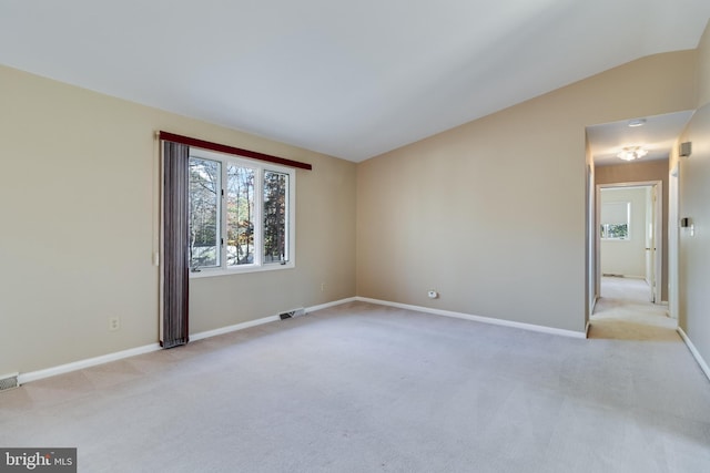 spare room featuring light carpet and vaulted ceiling