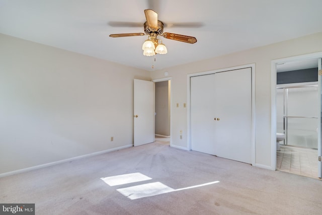 unfurnished bedroom with ceiling fan, a closet, light carpet, and ensuite bath