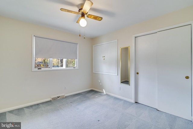 unfurnished bedroom with ceiling fan, light colored carpet, and a closet