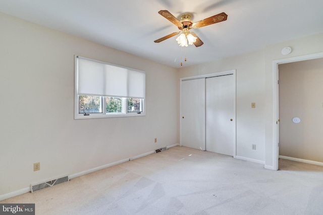 unfurnished bedroom with a closet, light colored carpet, and ceiling fan