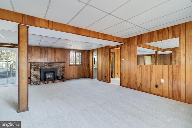 unfurnished living room featuring a paneled ceiling, light colored carpet, and wood walls