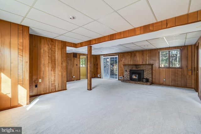 basement featuring wood walls, a drop ceiling, and light carpet