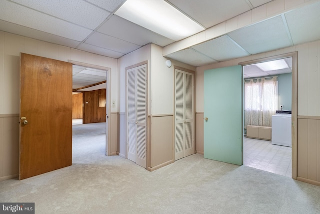 interior space with light carpet, washer / clothes dryer, and a drop ceiling