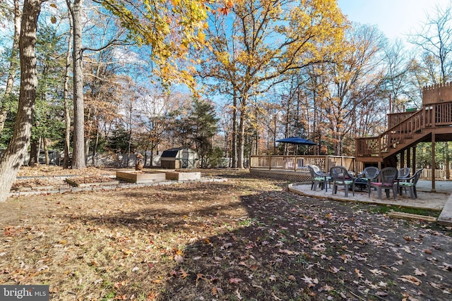 view of yard featuring a storage unit, a patio area, and a wooden deck