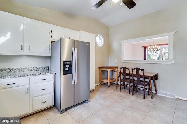 kitchen featuring light stone countertops, stainless steel refrigerator with ice dispenser, ceiling fan with notable chandelier, white cabinets, and lofted ceiling